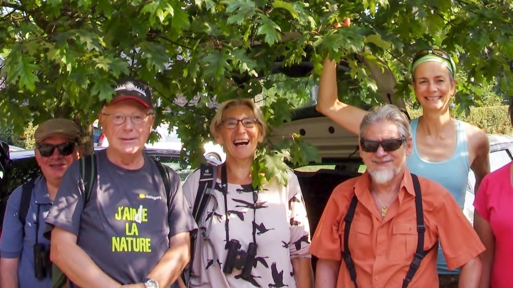 Un groupe de 11 adultes et 2 enfants, membres de la Régionale Natagora Condroz Mosan, posant et souriant pour la photo, sous un arbre lors d'une journée très ensoleillée.