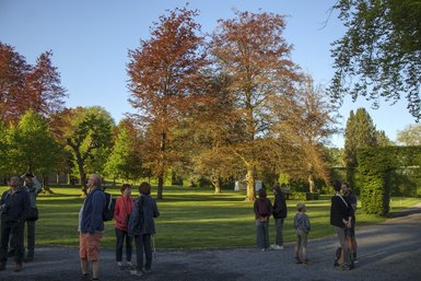 Photo des participants dans le parc du Château, certains utilisent des jumelles, certains discutent, d'autres observent en souriant.