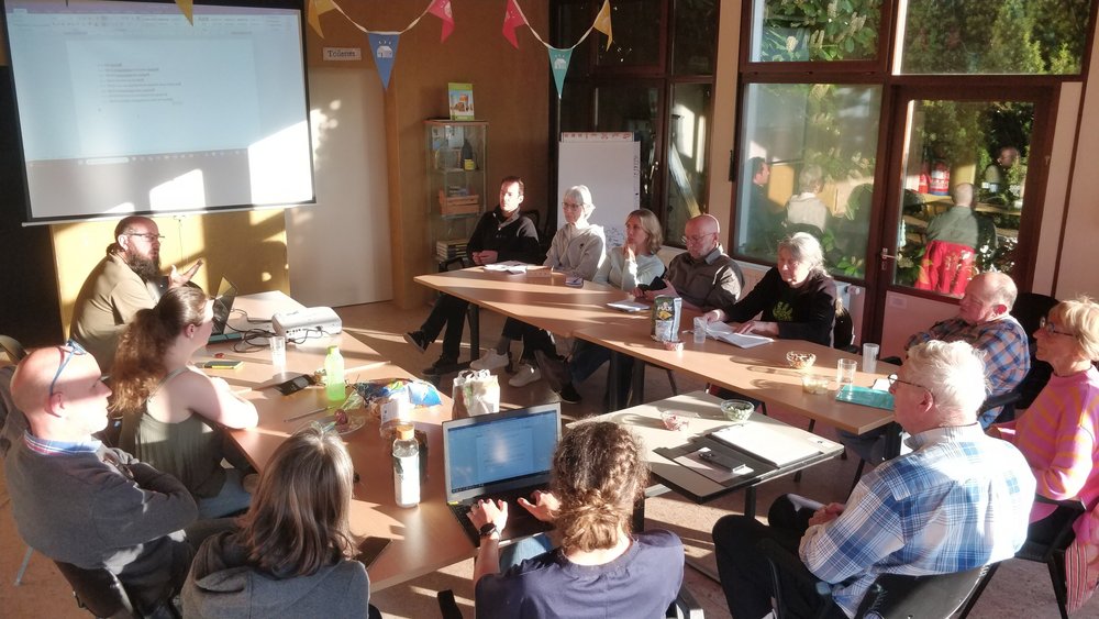 Photo de la salle où se tenait l'assemblée annuelle, on y voit les 13 participants autour d'une table placée en U.