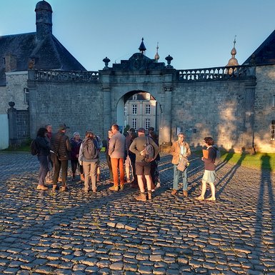 Photo des participants en groupe devant l'entrée de la cour du Château de Modave. Ils sont baignés des rayons du soleil du petit matin.