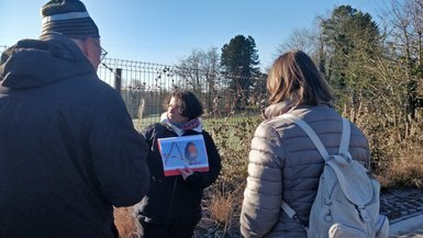 Une personne (Marie) présente une image de rougegorge familier aux participants de la balade.