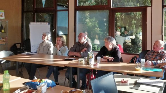 Cinq volontaires Natagora présents à la réunion de l'assemblée annuelle, regardant et écoutant attentivement la présentation.