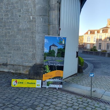 Photo de l'entrée du Château de Modave, avec une grande affiche du Syndicat d'Initiative et un panneau du CRIE de Modave.